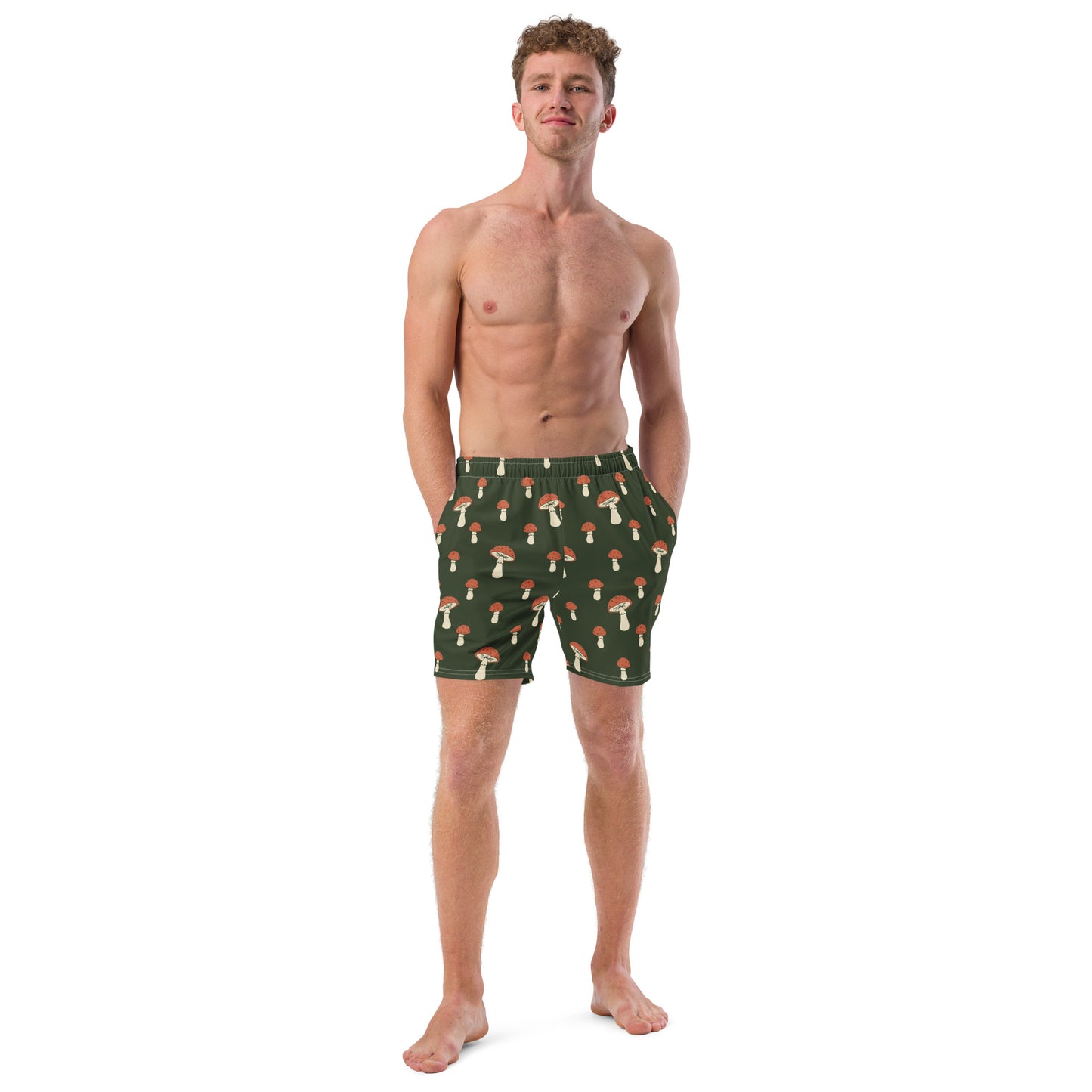 Man wearing swim trunks with pattern of mushrooms on a green background.