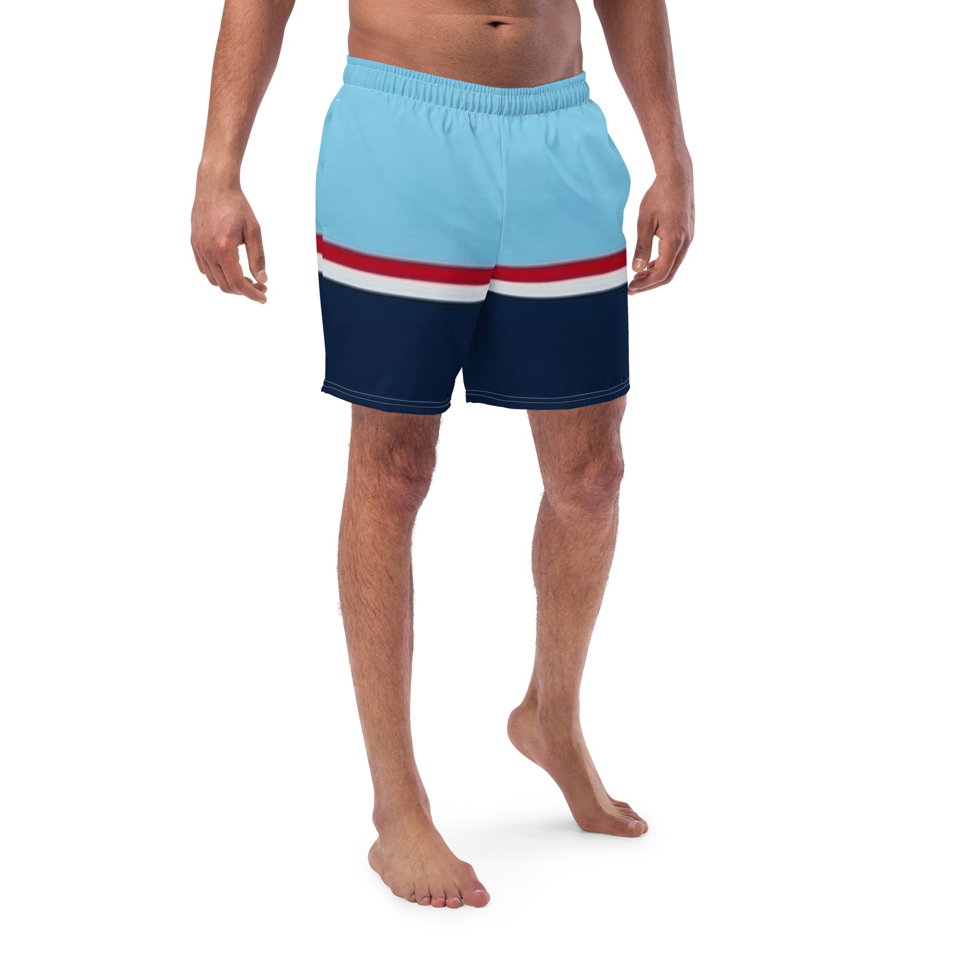 Man wearing swim trunks with pattern of light-blue on top, followed by a thinner red and thinner white line, followed by navy.