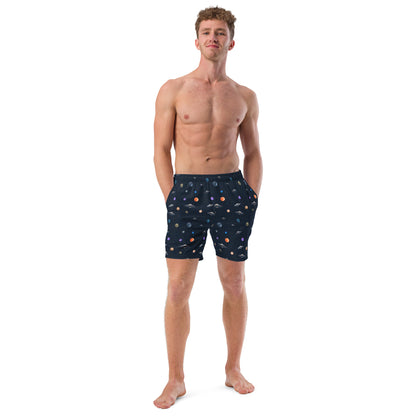 Man wearing swim trunks with graphic of planets and UFOs in space.