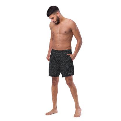 Man wearing swim trunks with black geometric pattern.