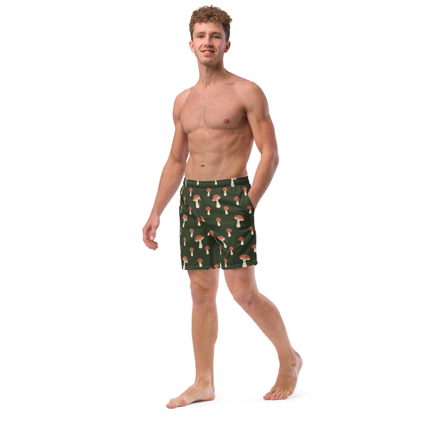 Man wearing swim trunks with pattern of mushrooms on a green background.