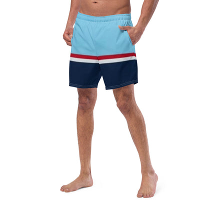 Man wearing swim trunks with pattern of light-blue on top, followed by a thinner red and thinner white line, followed by navy.