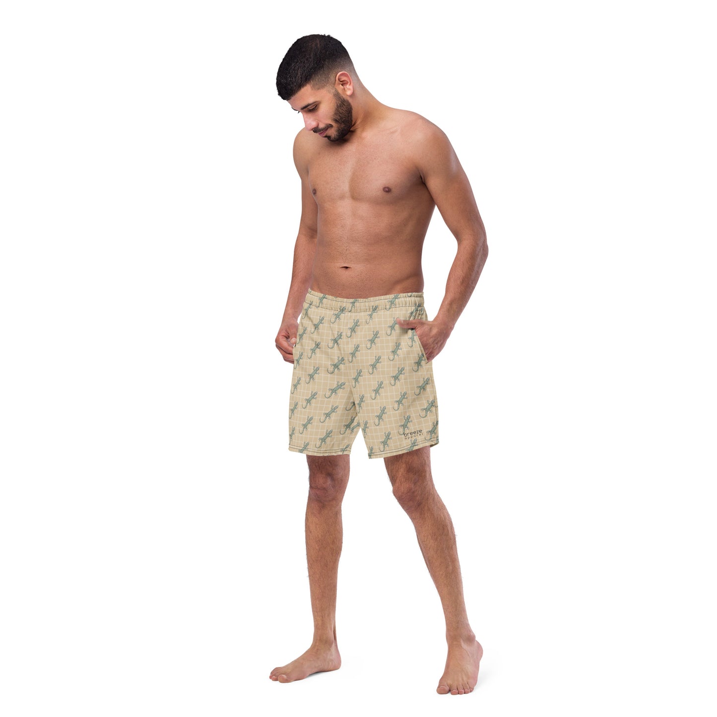 Man wearing beige swim trunks with pattern of green lizards.