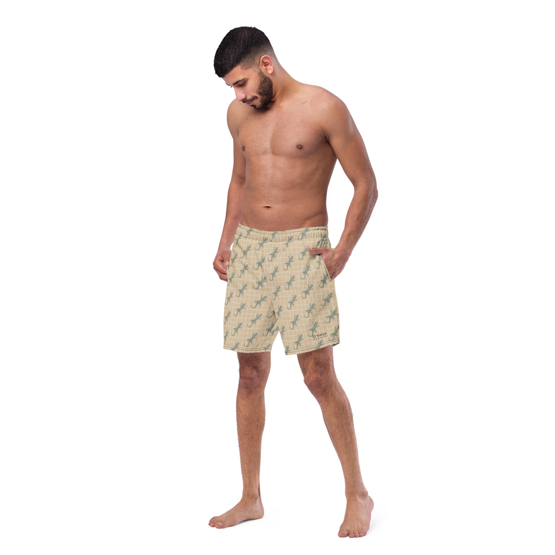 Man wearing beige swim trunks with pattern of green lizards.