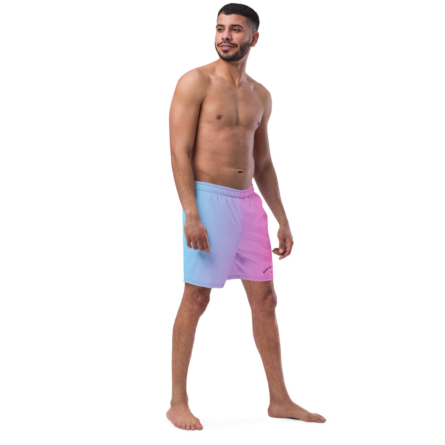 Man wearing swim trunks with a light-blue-to-pink design and a black 'Breeze Apparel Miami' word logo on the bottom-left knee