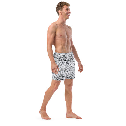 Man wearing swim trunks with pattern of black splotches on a white background.