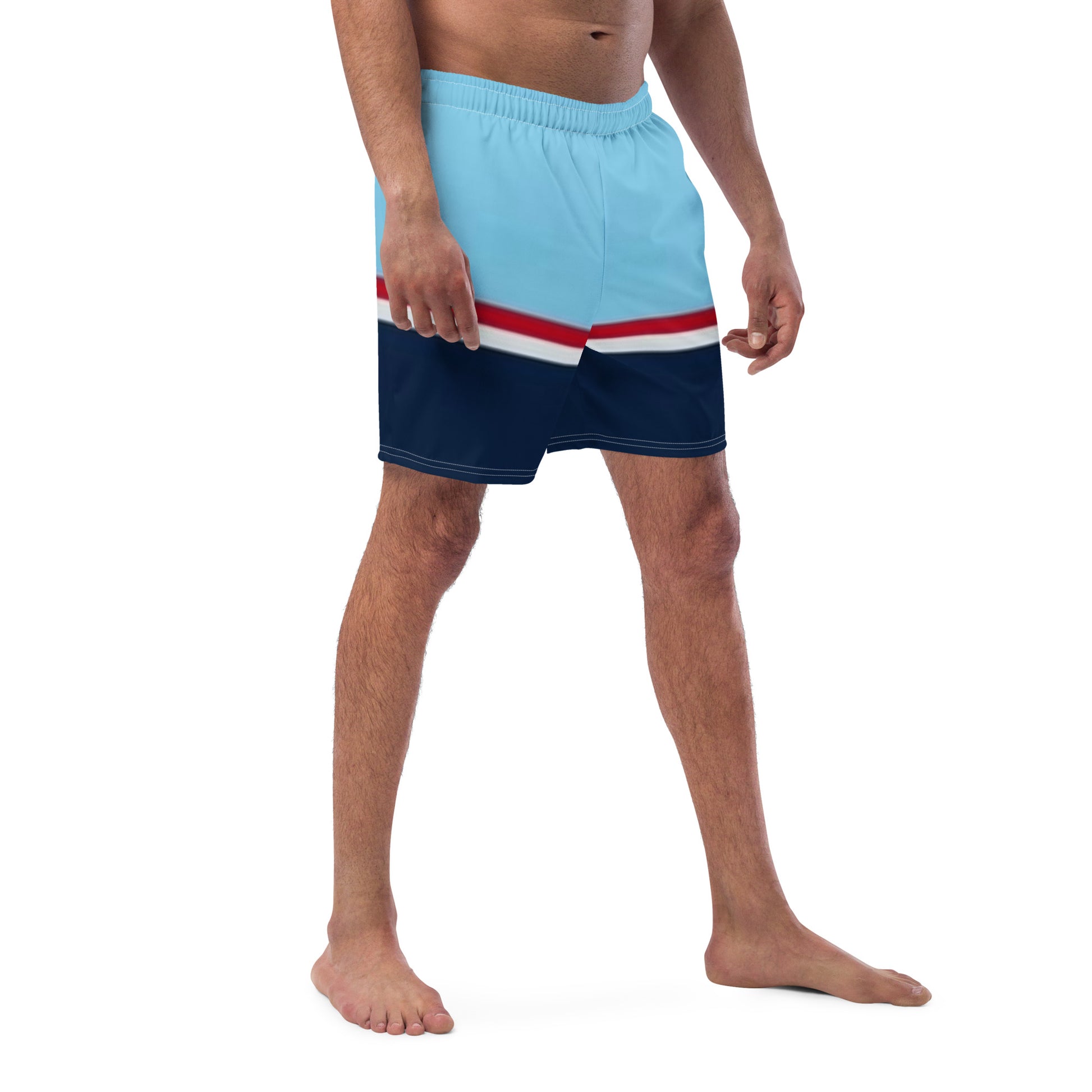 Man wearing swim trunks with pattern of light-blue on top, followed by a thinner red and thinner white line, followed by navy.