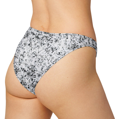 Rear view of woman wearing bikini bottom with pattern of black splotches set on white background.