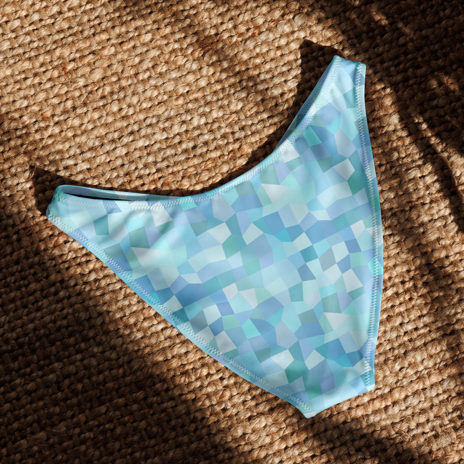 Back of bikini bottom with cyan geometric pattern, laying in sunlight.
