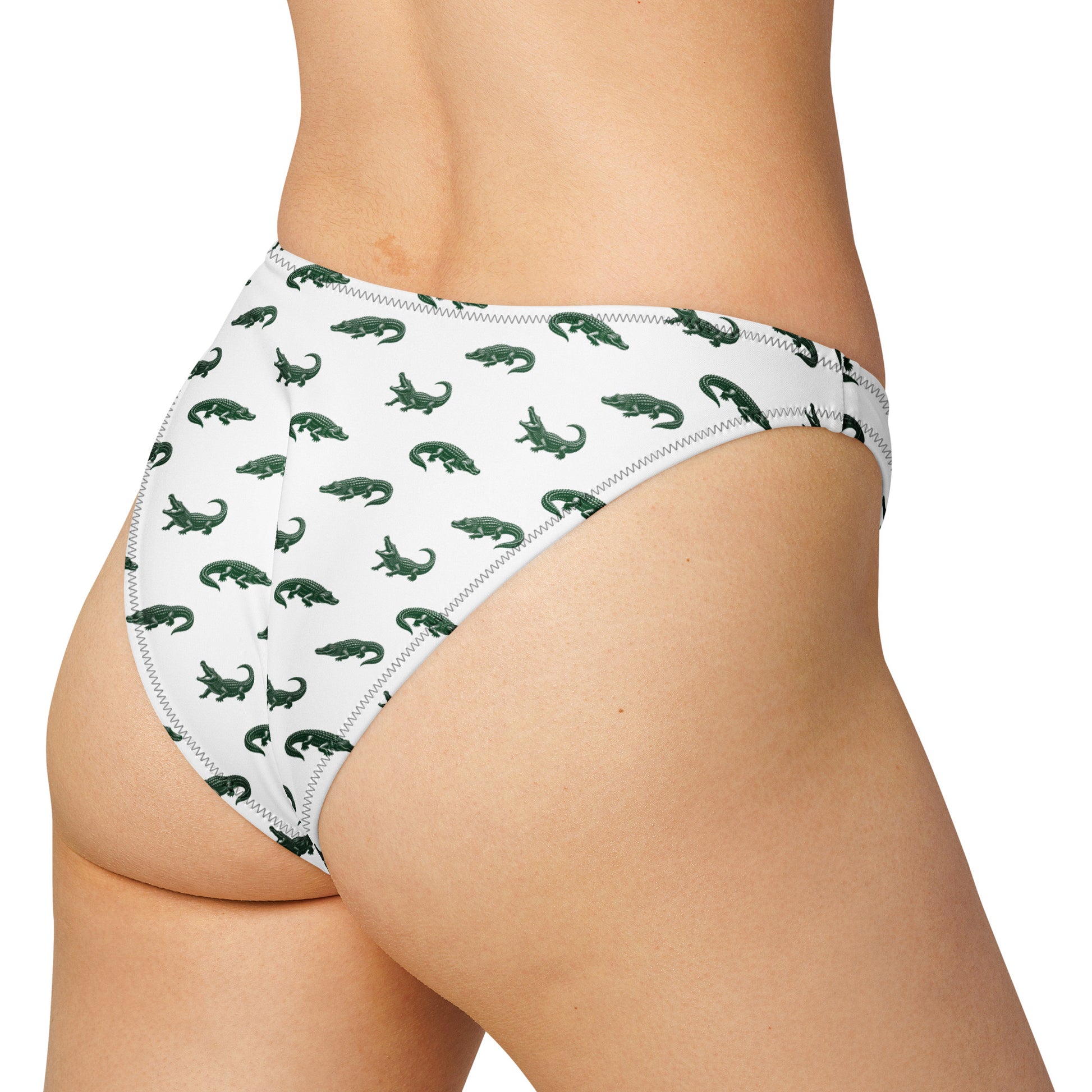 Woman wearing bikini bottom with pattern of green alligators.
