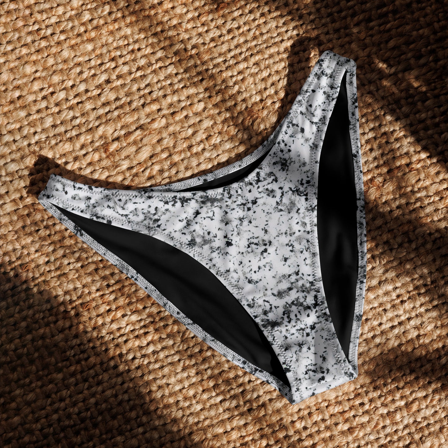 Bikini bottom with pattern of black splotches set on white background, laying in sunlight.