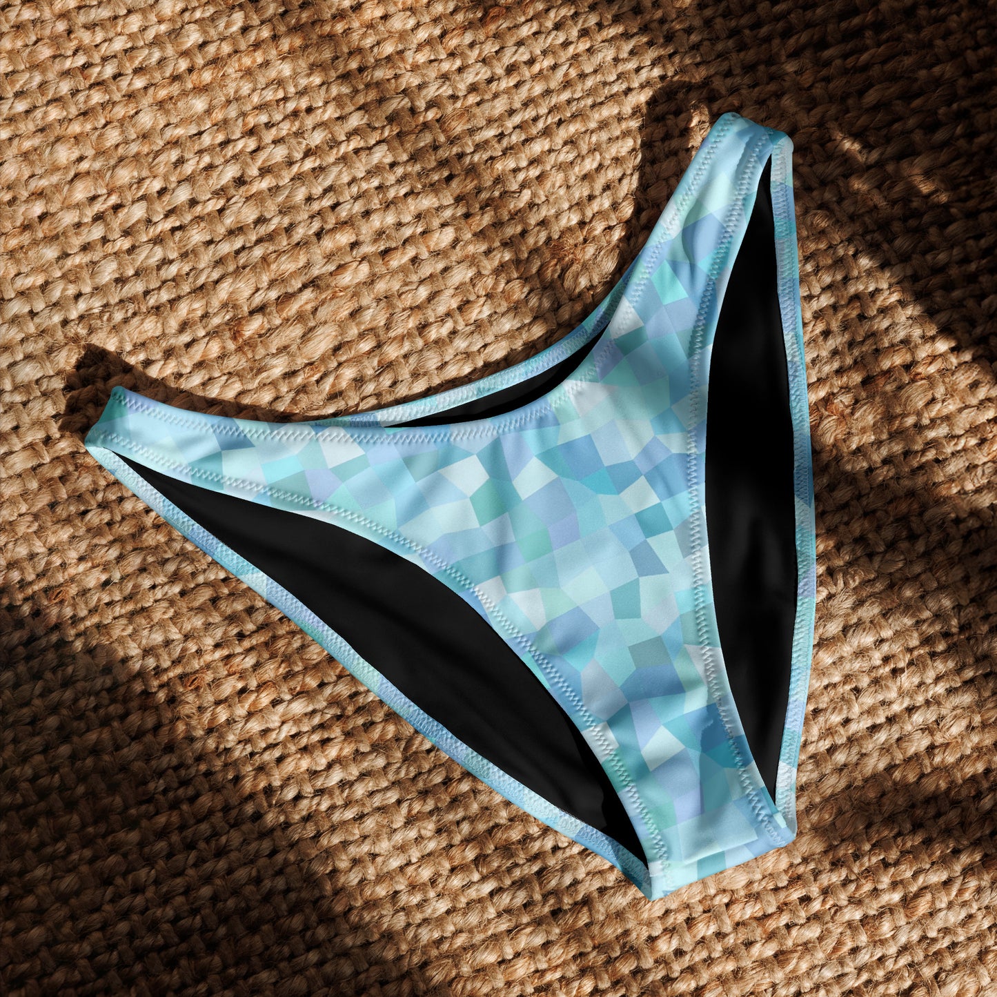 Bikini bottom with cyan geometric pattern, laying in sunlight.
