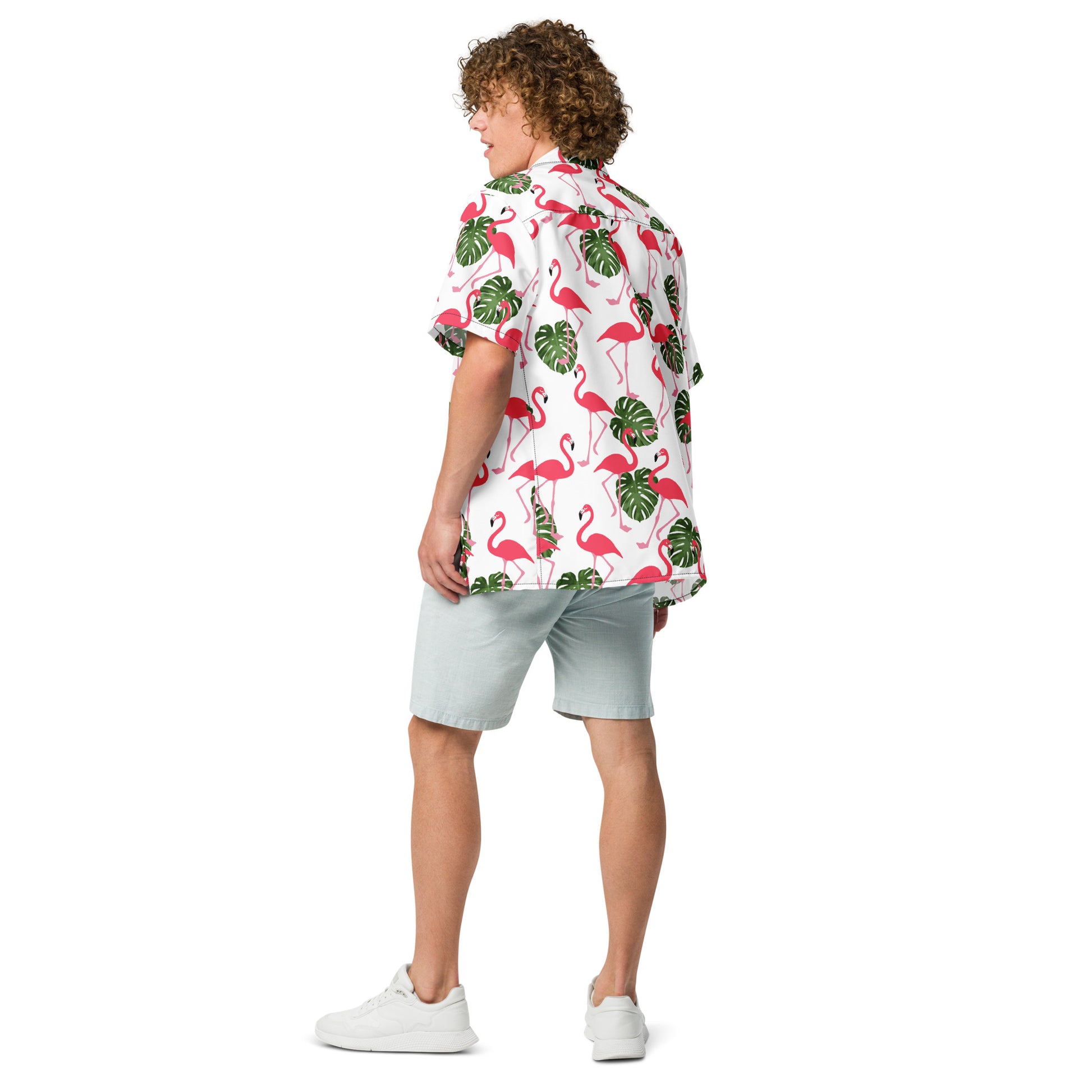 Rear view of man wearing button-down shirt with pattern of flamingos and green palm leaves set on a white background.