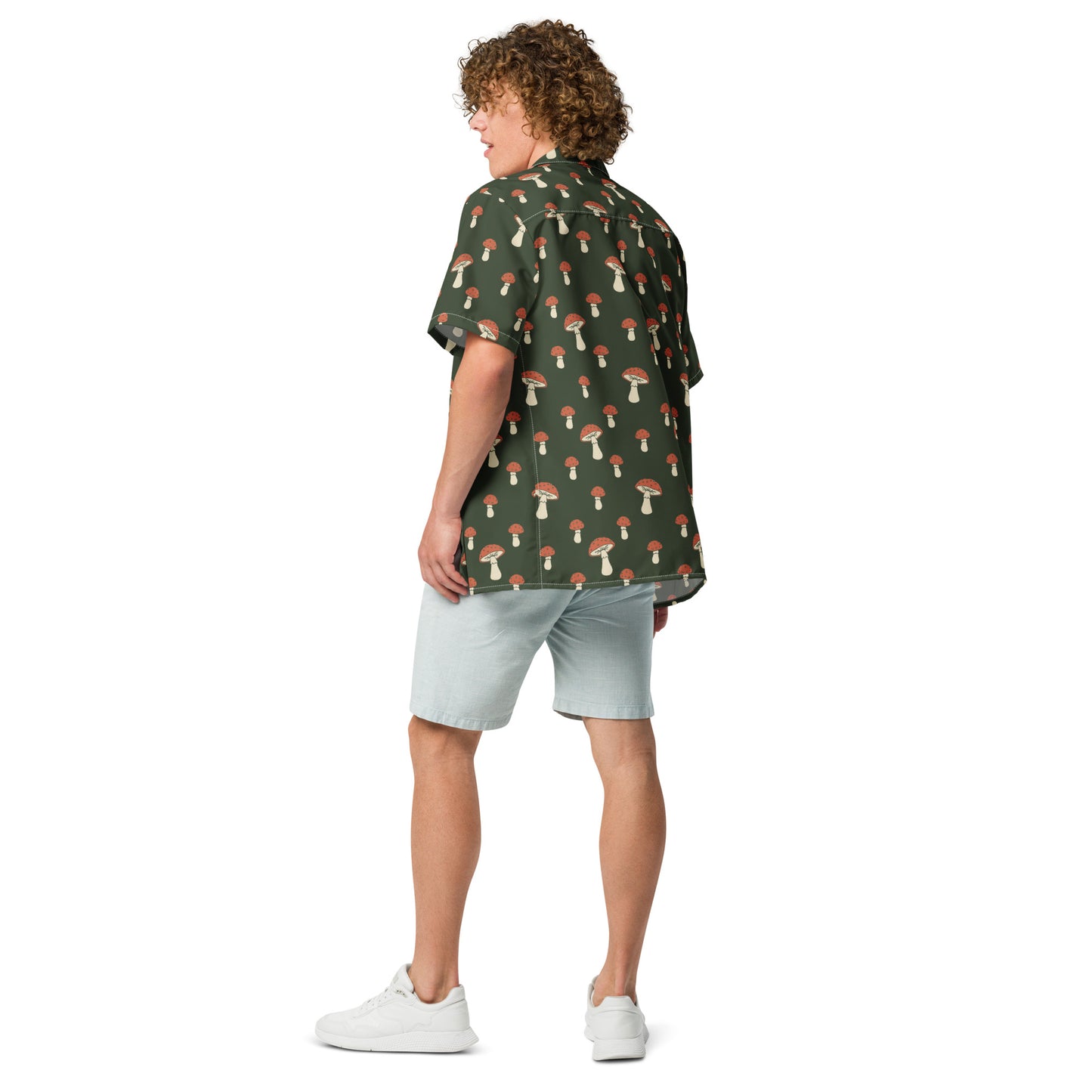 Rear view of man wearing button-down shirt with pattern of mushrooms set on a green background.