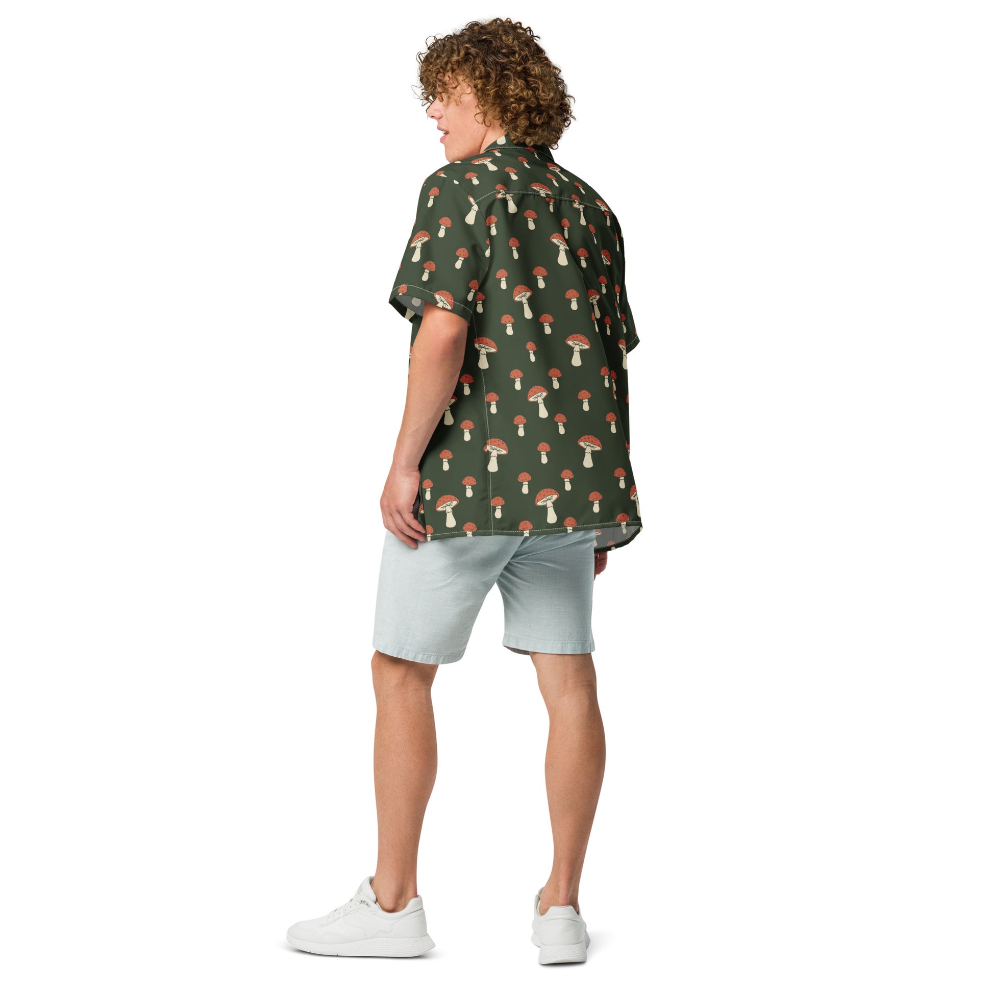 Rear view of man wearing button-down shirt with pattern of mushrooms set on a green background.
