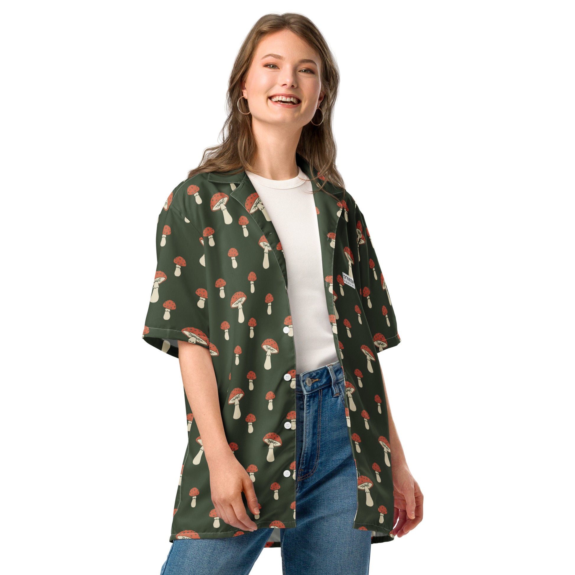 Woman wearing button-down shirt with pattern of mushrooms set on a green background.