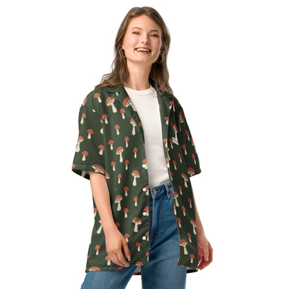 Woman wearing button-down shirt with pattern of mushrooms set on a green background.