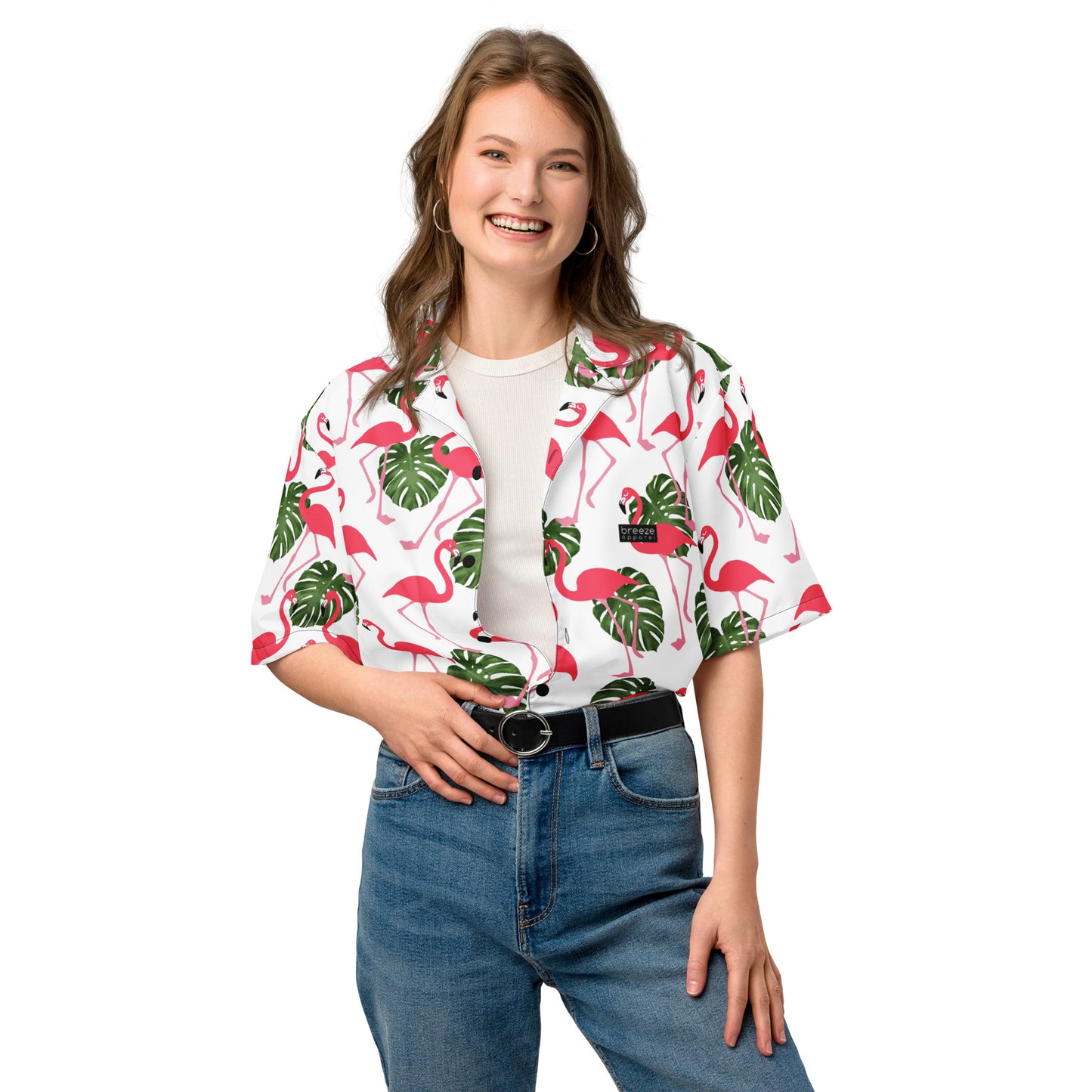 Woman wearing button-down shirt with pattern of flamingos and green palm leaves set on a white background.