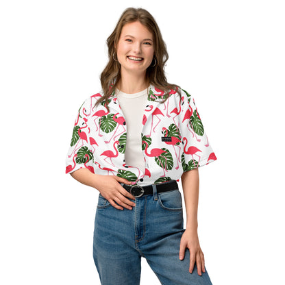 Woman wearing button-down shirt with pattern of flamingos and green palm leaves set on a white background.