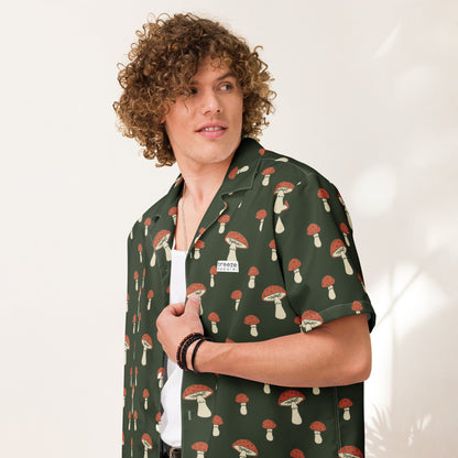 Man wearing button-down shirt with pattern of mushrooms set on a green background.
