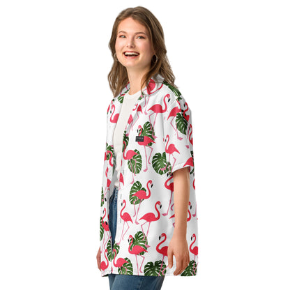 Woman wearing button-down shirt with pattern of flamingos and green palm leaves set on a white background.