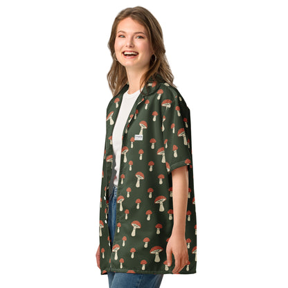 Woman wearing button-down shirt with pattern of mushrooms set on a green background.