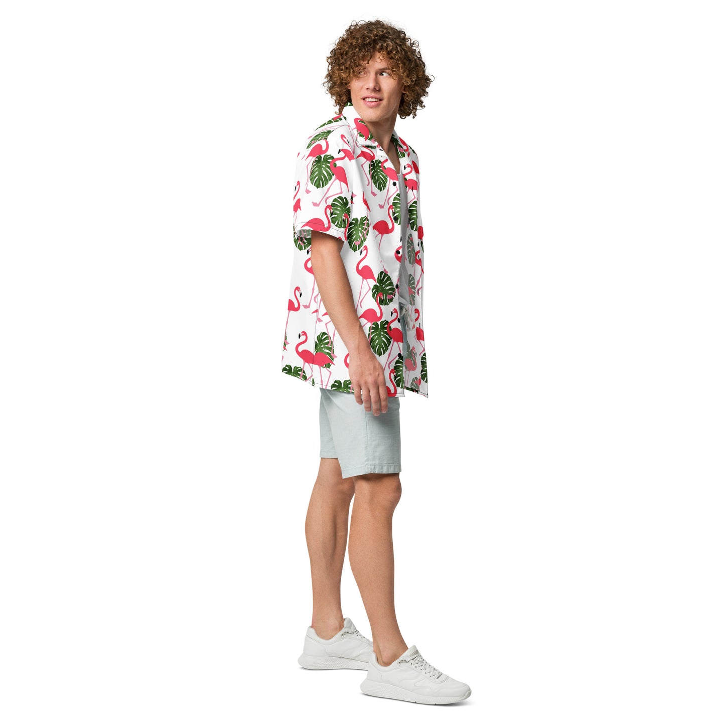 Man wearing button-down shirt with pattern of flamingos and green palm leaves set on a white background.