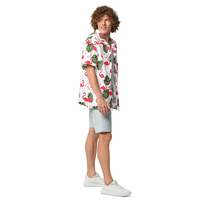 Man wearing button-down shirt with pattern of flamingos and green palm leaves set on a white background.