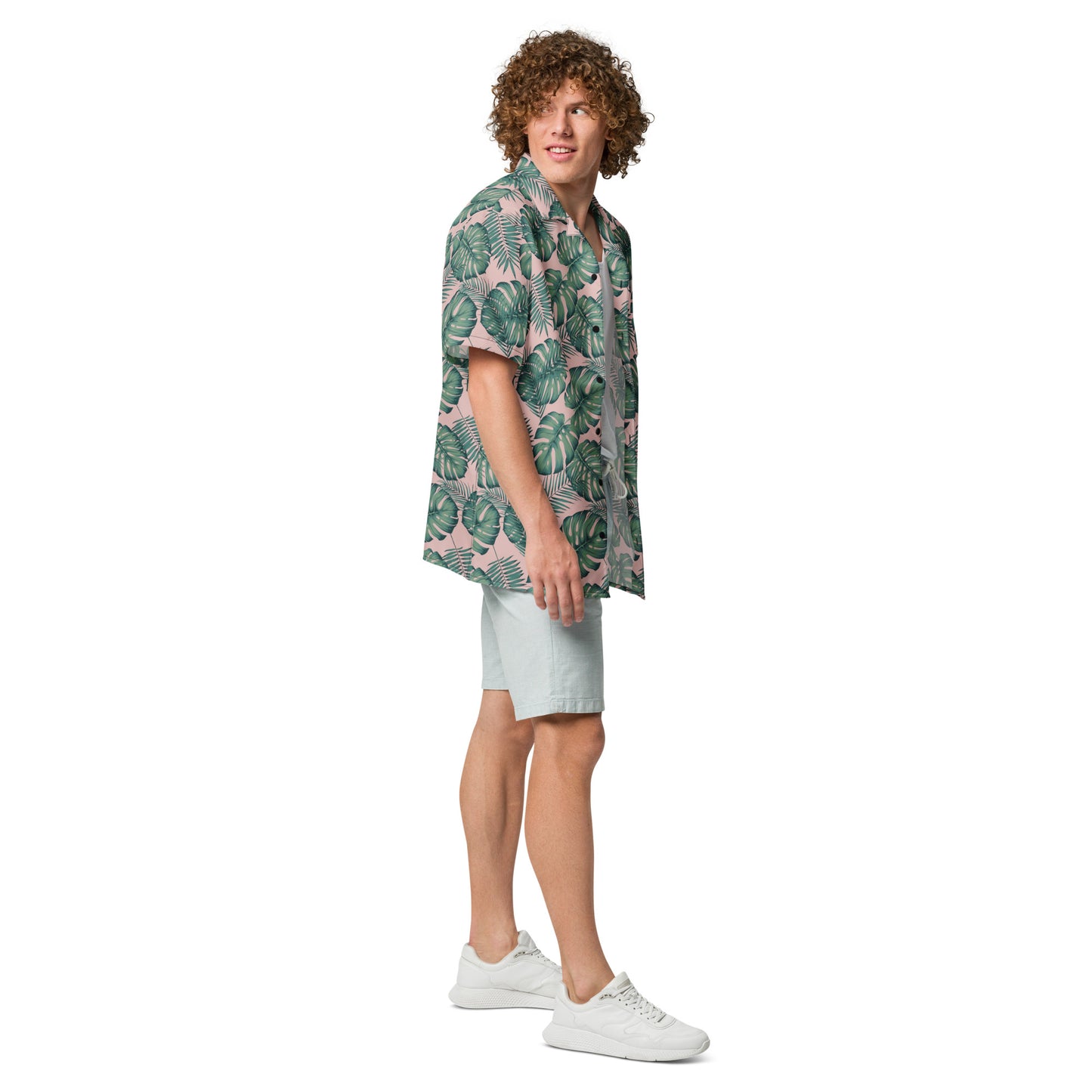Man wearing button-down shirt with pattern of green palm leaves set on a pink background.