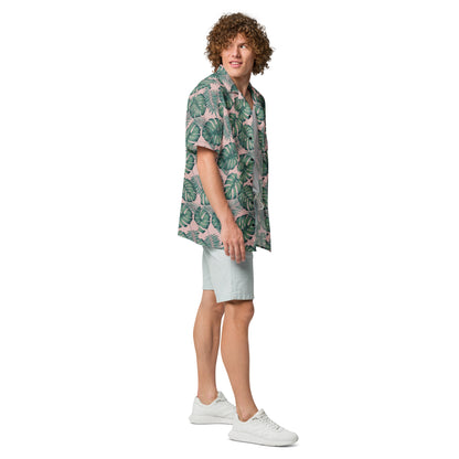 Man wearing button-down shirt with pattern of green palm leaves set on a pink background.