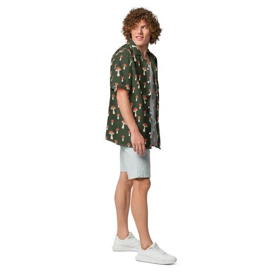 Man wearing button-down shirt with pattern of mushrooms set on a green background.