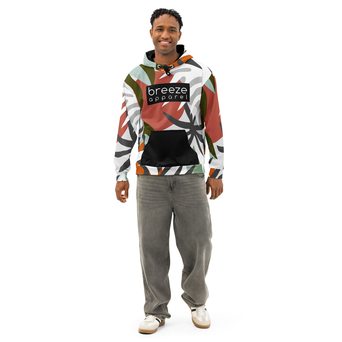 Woman wearing hoodie with a red, black, green, orange, and white floral-geometric design, with a black pocket, black drawstrings, and a 'breeze apparel' logo  consisting of white wording set in a black rectangle across the chest.