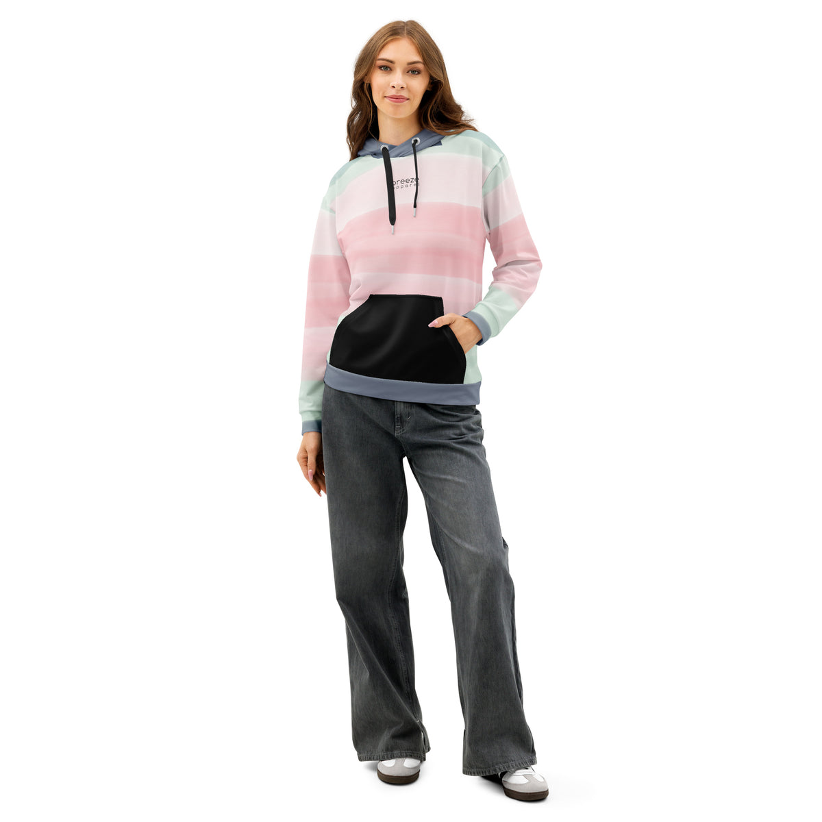 Woman wearing hoodie with colors light pastel green, shades of pink, and gray in stripes, a black pocket, and 'breeze apparel' written in small text on chest.