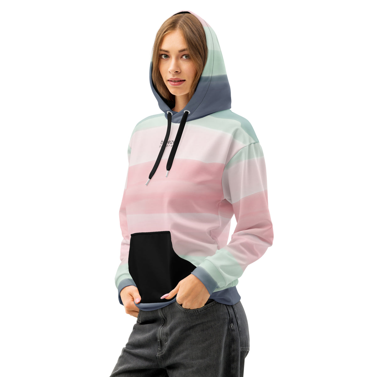 Woman wearing hoodie with colors light pastel green, shades of pink, and gray in stripes, a black pocket, and 'breeze apparel' written in small text on chest.