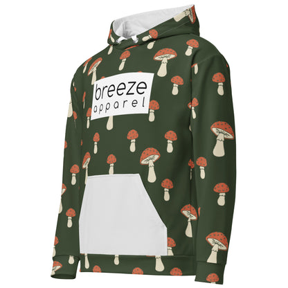Forest-green hoodie with all-over mushroom pattern. Hoodie interior and pocket are light gray; drawstrings are white. A white rectangle with 'breeze apparel' written in black is across the chest.