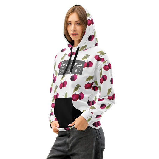 Woman wearing a white hoodie with an all-over cherries design. Across the chest is a gray rectangle with 'breeze apparel' in white inside. Hood interior, drawstrings, and pocket are black.