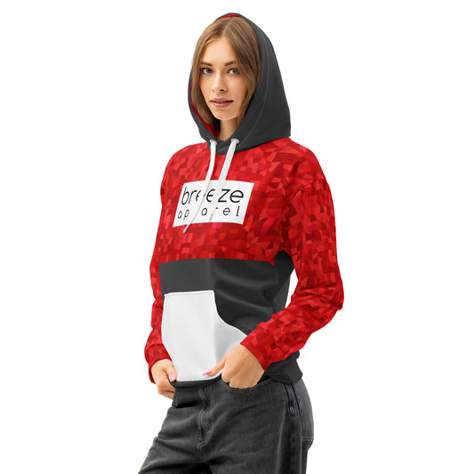 Woman wearing hoodie with a red geometric pattern on upper half, sleeves and hood interior, with a white pocket, white drawstrings tucked inside, and a 'breeze apparel' logo consisting of black wording set in a white rectangle across the chest. Behind pocket and on outside of hood is dark gray.