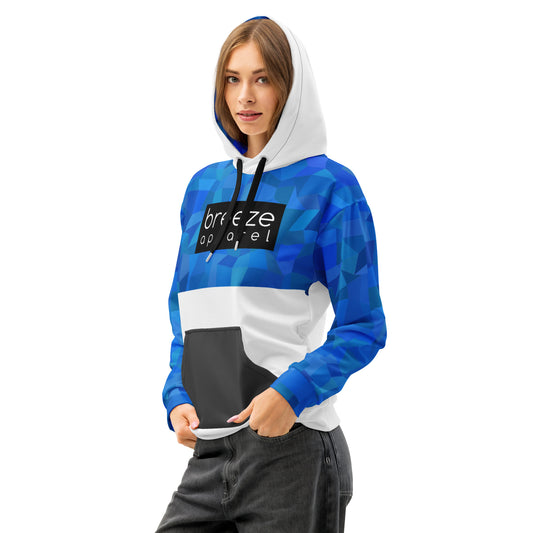 Woman wearing hoodie with blue geometric pattern on top half, hood interior, and sleeves, a black box with 'breeze apparel' in white inside across chest, a dark-gray pocket. Drawstrings are black, while hood and bottom half are white.