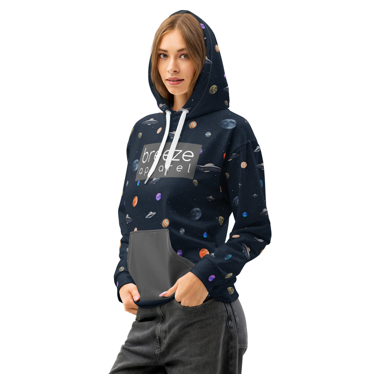 Woman wearing hoodie with pattern of UFOs and planets in space. Chest is overlaid with gray, rectangular logo with white lettering; hood interior and pocket are gray.