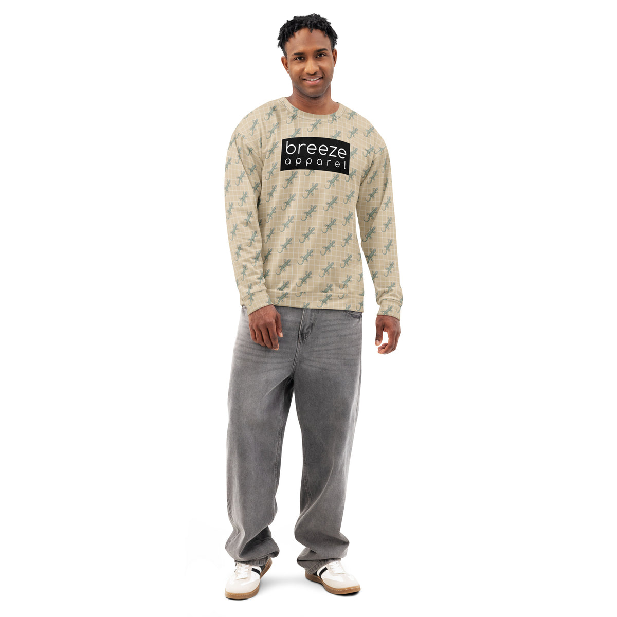 Man wearing beige sweatshirt with pattern of green geckos. Across chest is black, rectangular logo with white lettering.