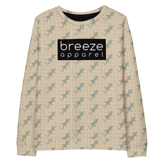 Beige sweatshirt with pattern of green geckos. Across chest is black, rectangular logo with white lettering.