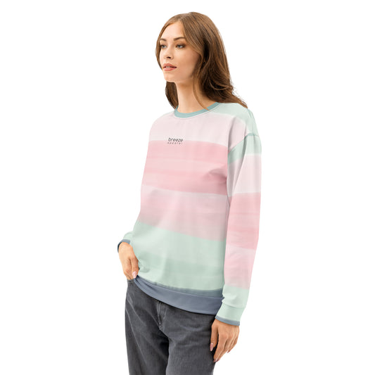 Woman wearing sweatshirt with colors light pastel green, shades of pink, and gray in stripes, and 'breeze apparel' written in small text on chest.
