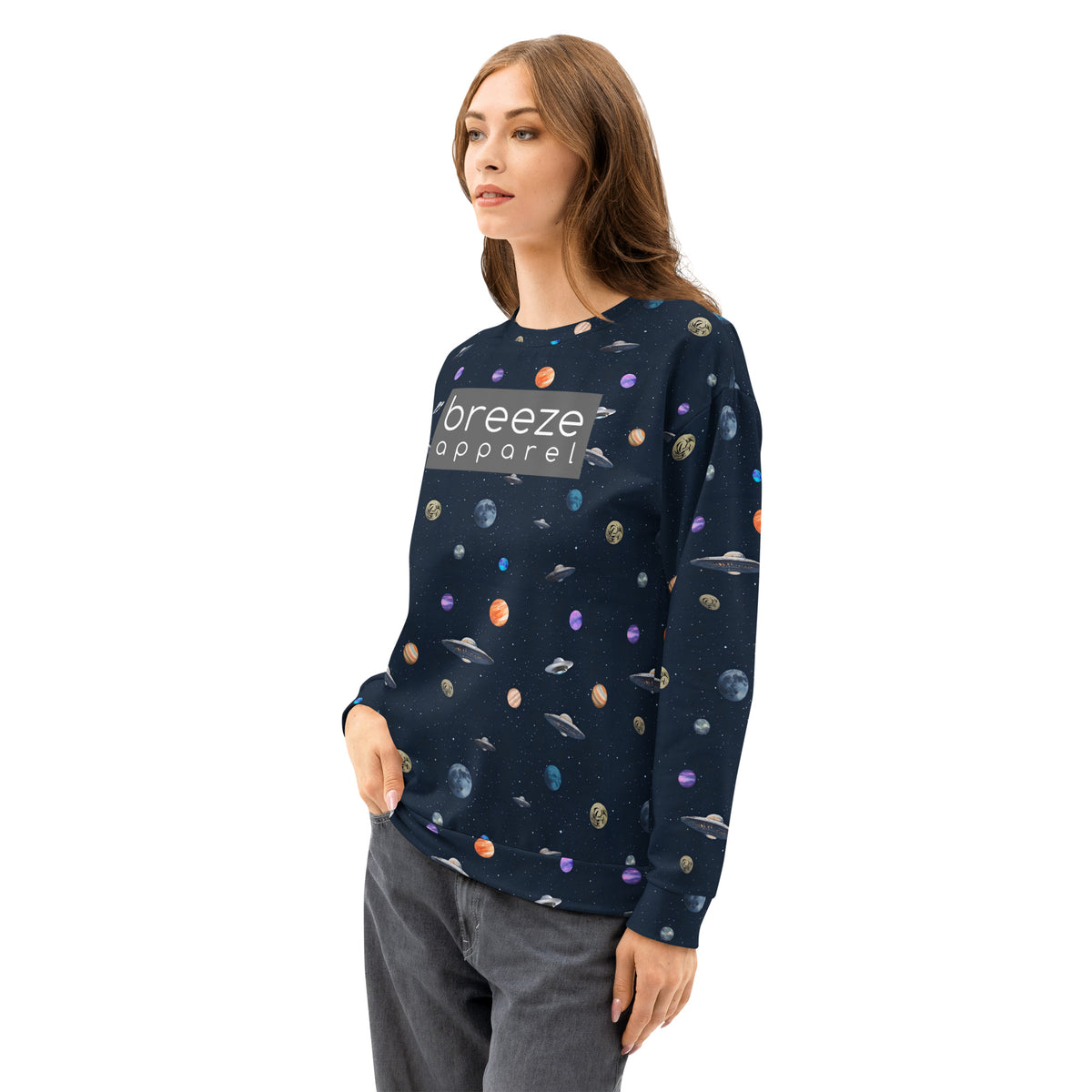 Woman wearing sweatshirt with pattern of UFOs and planets in space. Chest is overlaid with gray, rectangular logo with white lettering.