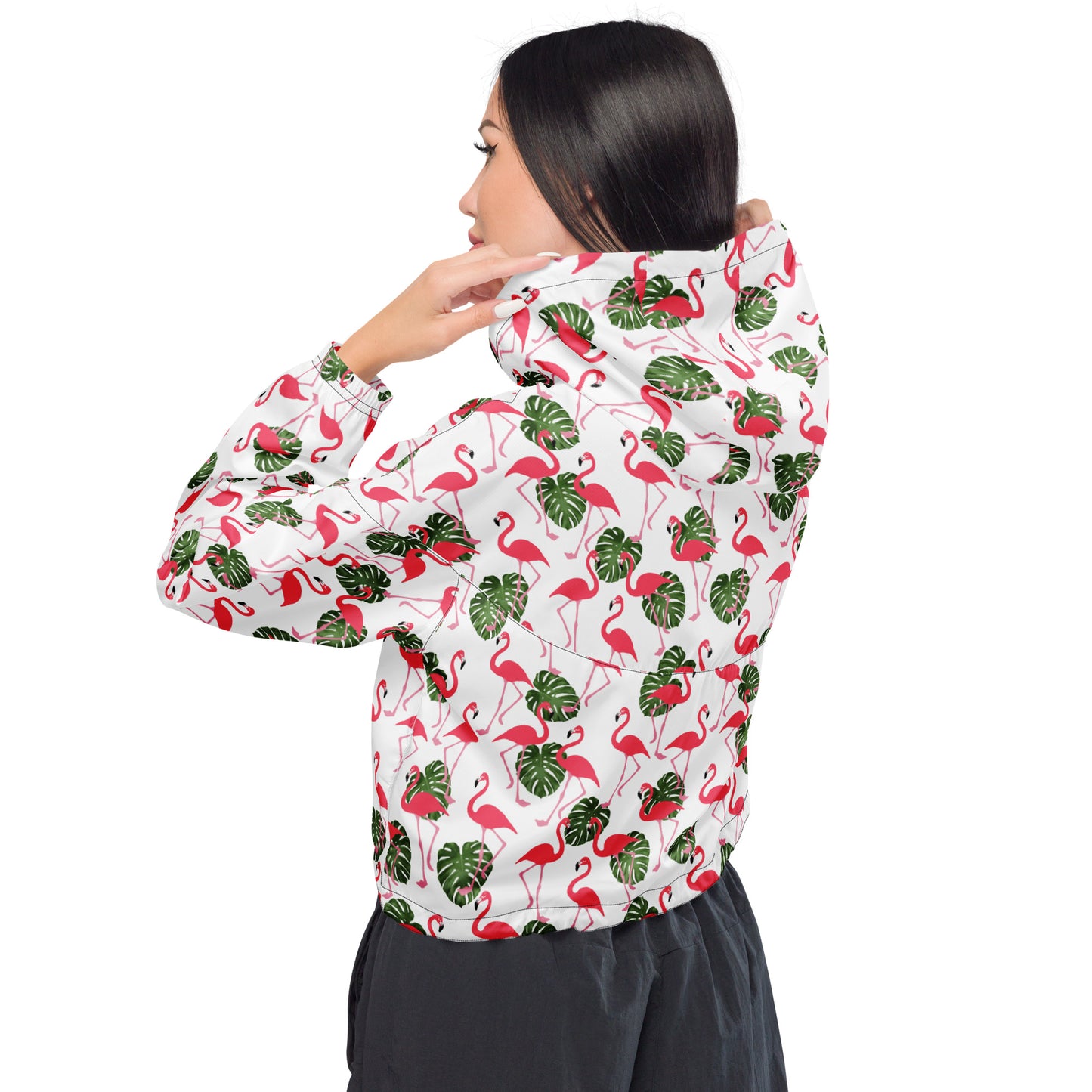 Woman wearing cropped jacket with pattern of flamingos on a white background.