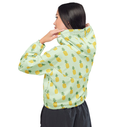 Woman wearing cropped jacket with pattern of pineapples set on a light-green background.