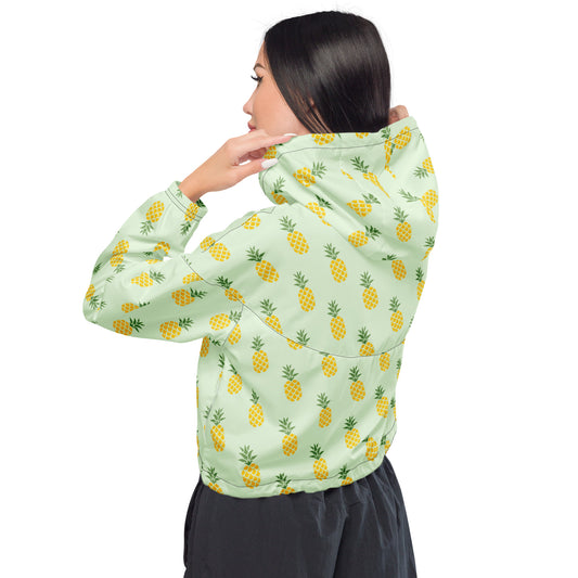 Woman wearing cropped jacket with pattern of pineapples set on a light-green background.