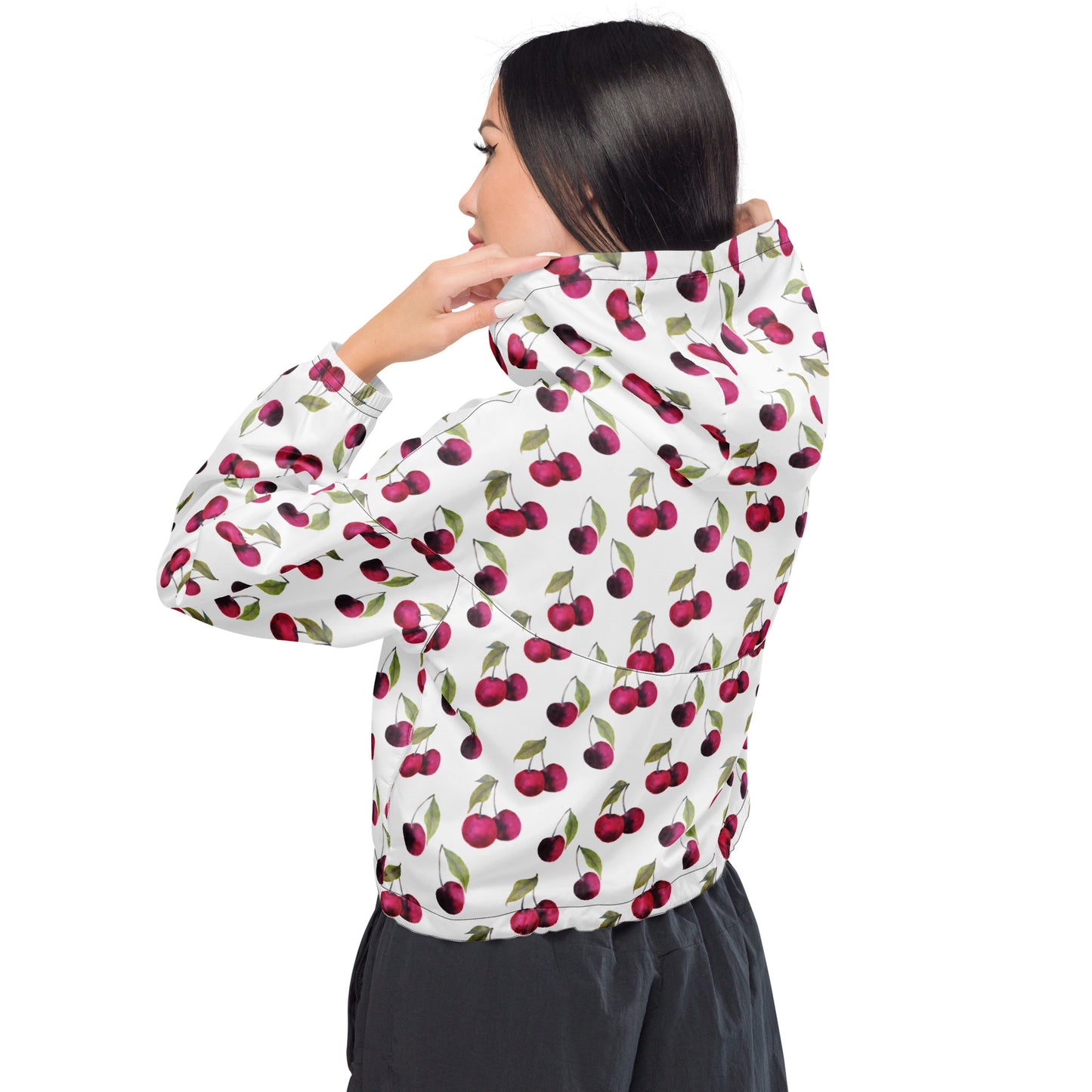 Woman wearing jacket with pattern of cherries on a white background.