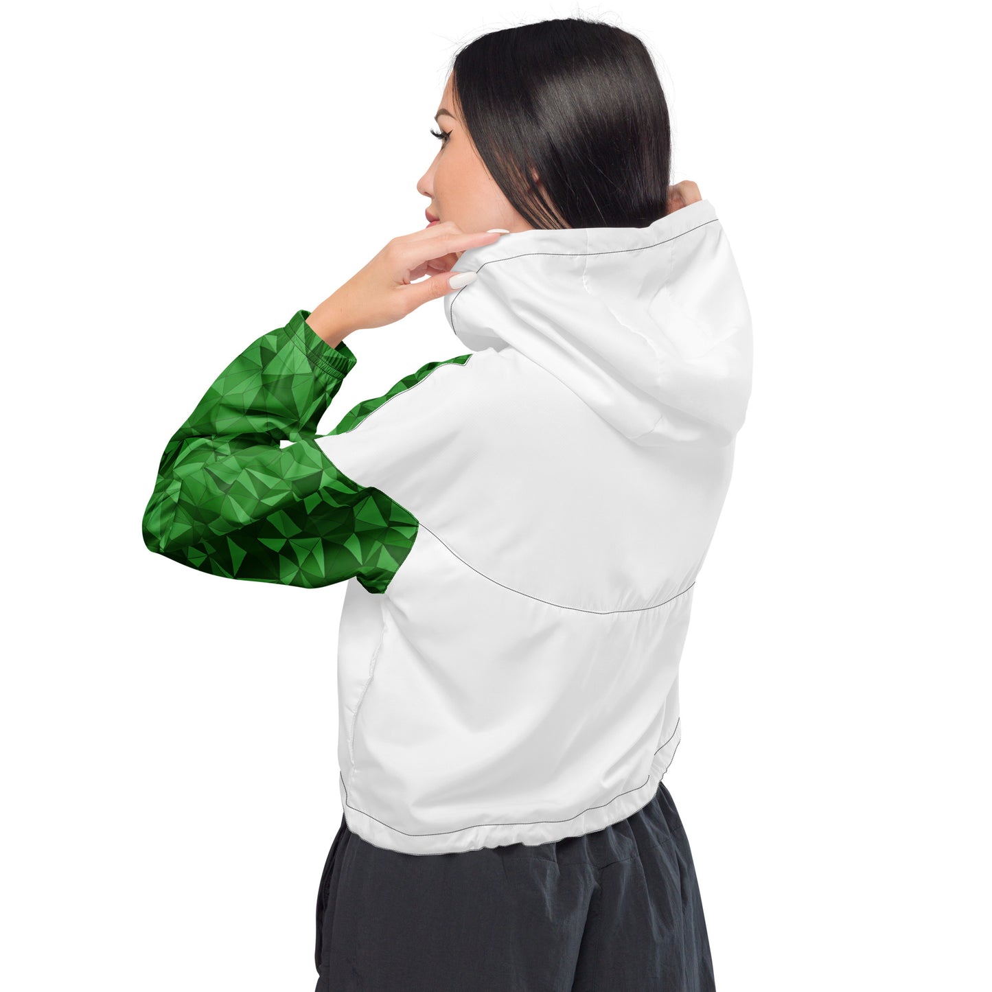 Rear view of woman wearing cropped windbreaker that's white, except for a green geometric pattern on sleeves.
