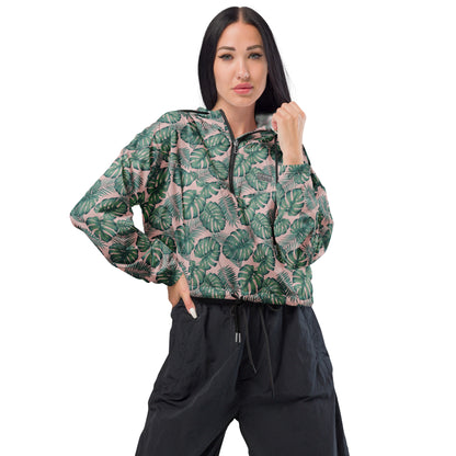Woman wearing cropped jacket with pattern of green palm leaves set on a pink background.