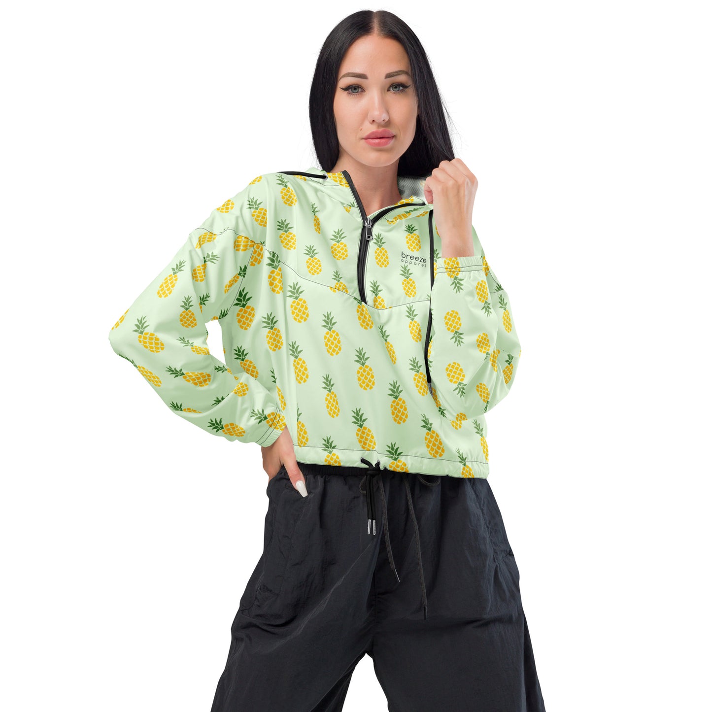 Woman wearing cropped jacket with pattern of pineapples set on a light-green background.